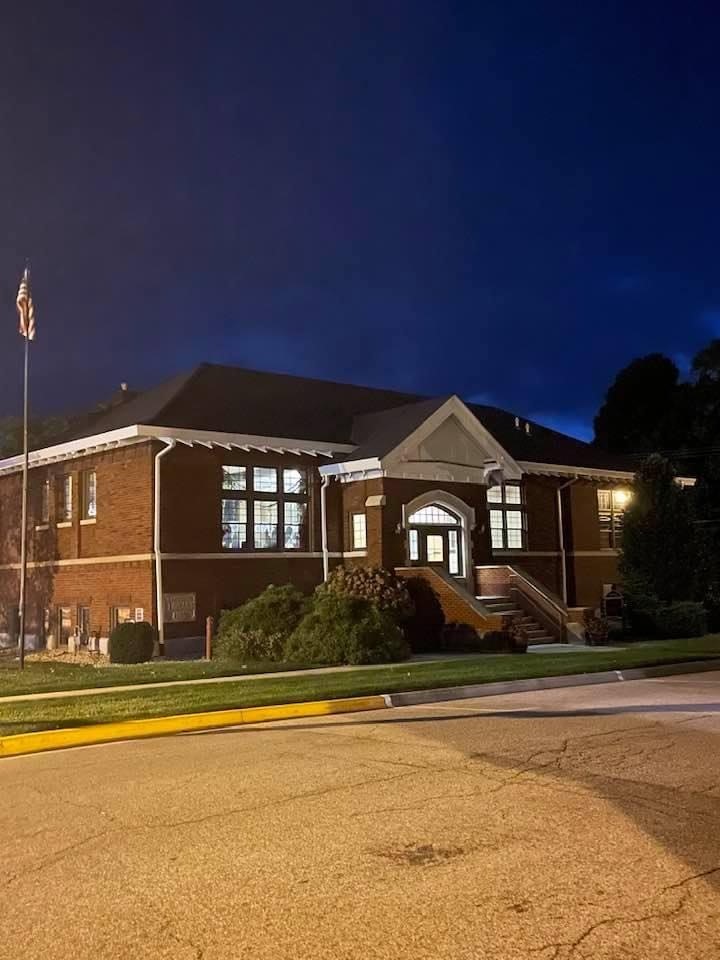 a photo of the front of the library at nighttime, with the windows lit up inside